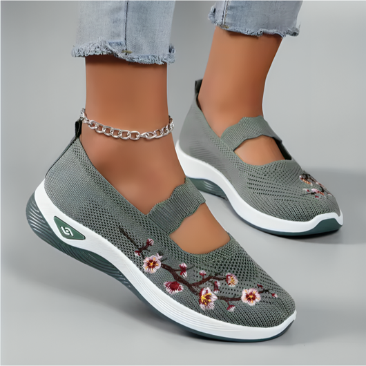 Person iklädd gröna mesh-damskor med blomsterbroderi och elastisk rem, lifestyle-bild med jeans och fotlänk