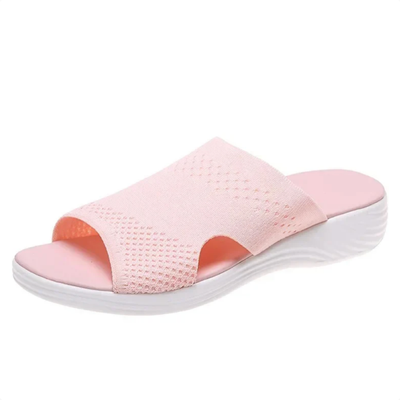 Damtoffla i rosa mesh med öppen tå och vit stötdämpande sula, sedd snett framifrån