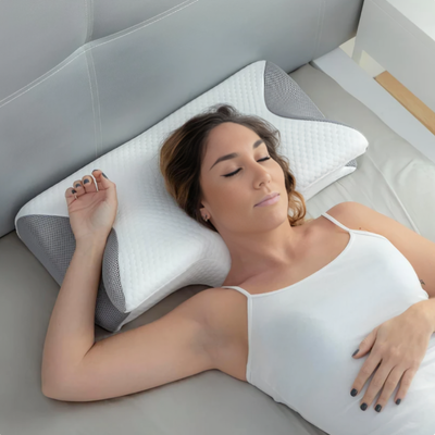 Kvinna som sover på rygg på ergonomisk minnesskumskudde med grå meshkanter