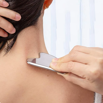 Kvinna använder Gua Sha massageskrapa på nacke och axel