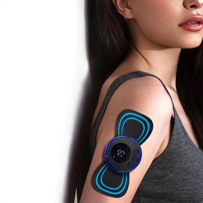 Kvinna med EMS & TENS massageplatta fäst på överarmen – svart enhet med blå LED-ring och LCD-display