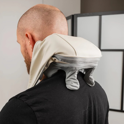 Man använder nackmassageapparaten över nacke och axlar, sedd bakifrån